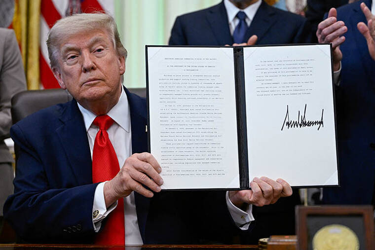 REUTERS/DANIEL HEUER
President Donald Trump holds a proclamation for restoring American commercial fishing in the Pacific, after signing it today in the Oval Office at the White House in Washington, D.C.