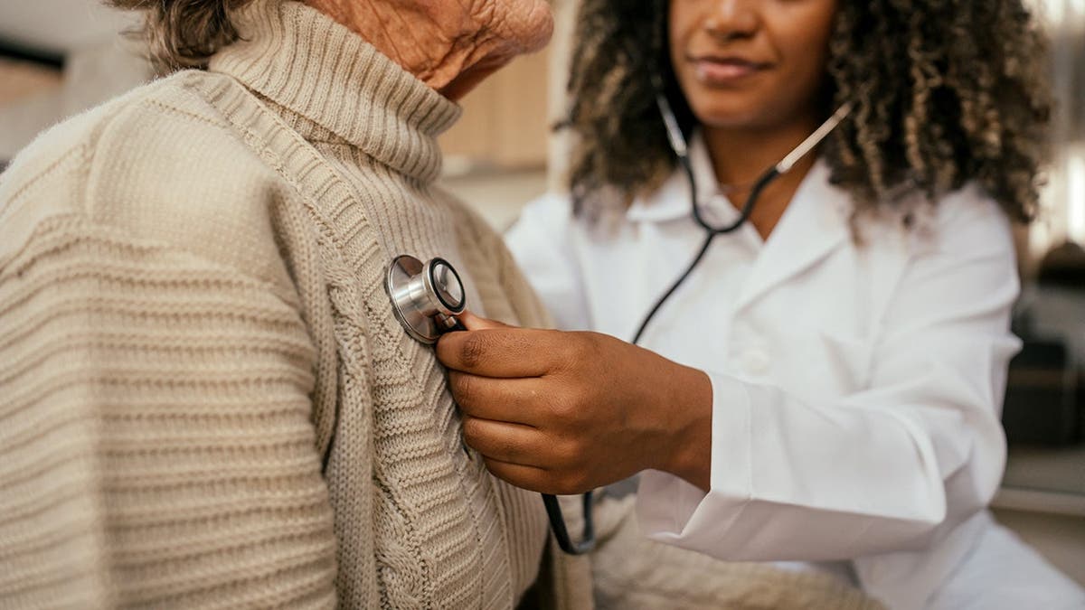 A woman has her heart listened to by a doctor.