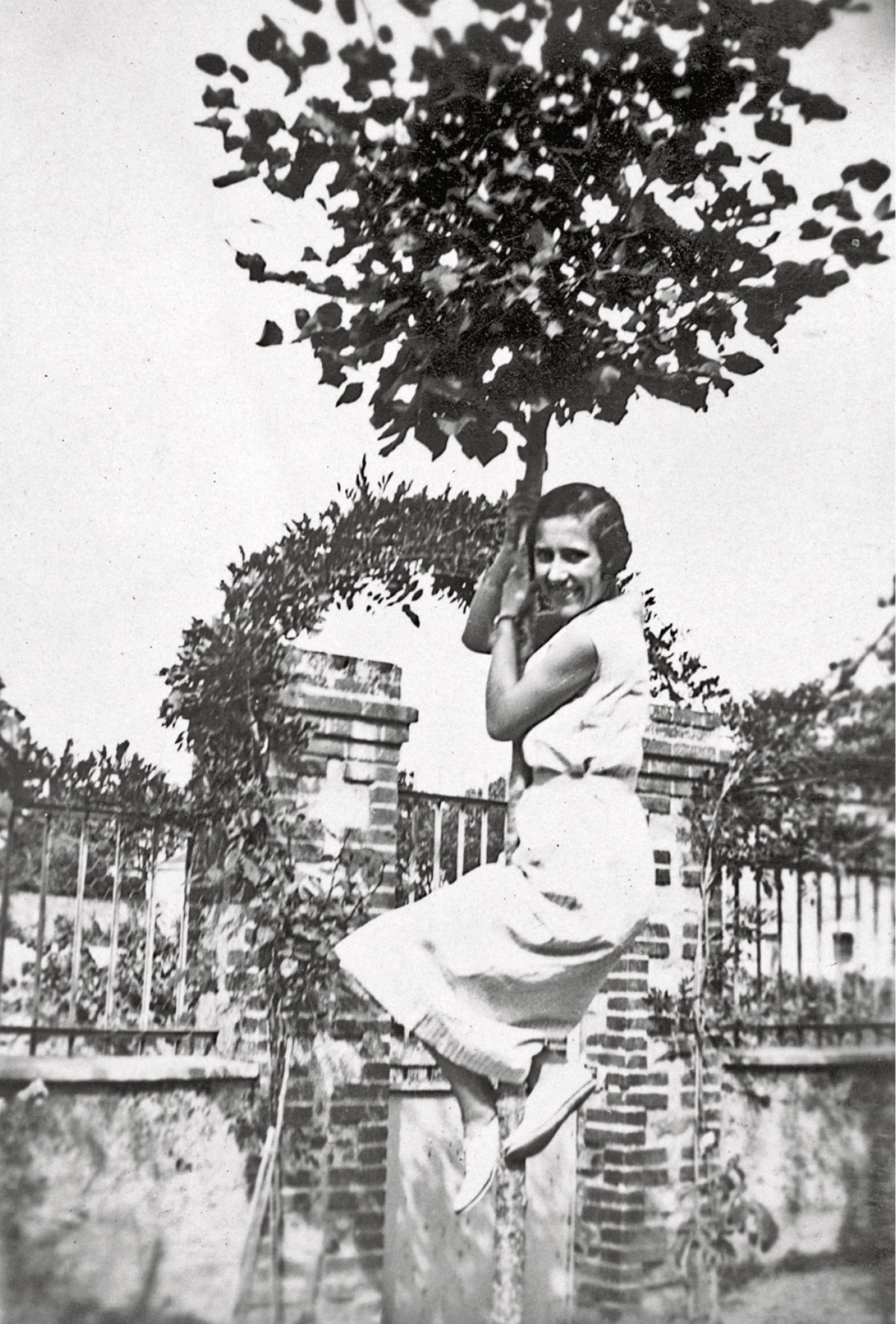 a black-and-white snapshot of a woman in a tree