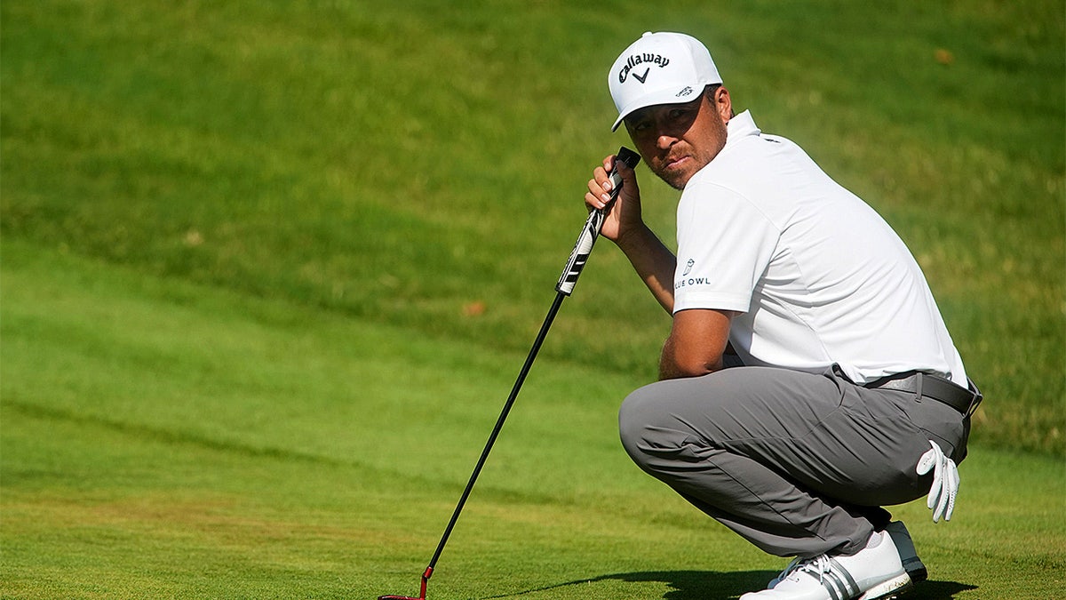 Xander Schauffele looking toward Aldrich Potgieter chipping onto the green at the ninth hole.