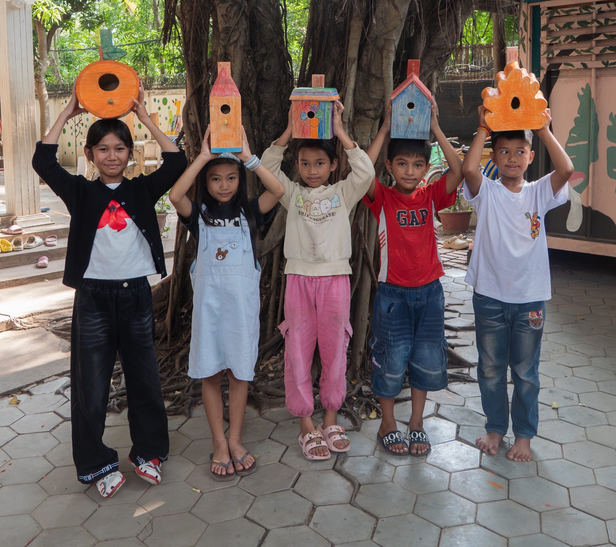 five children hold up whimsical birdhouses that they designed