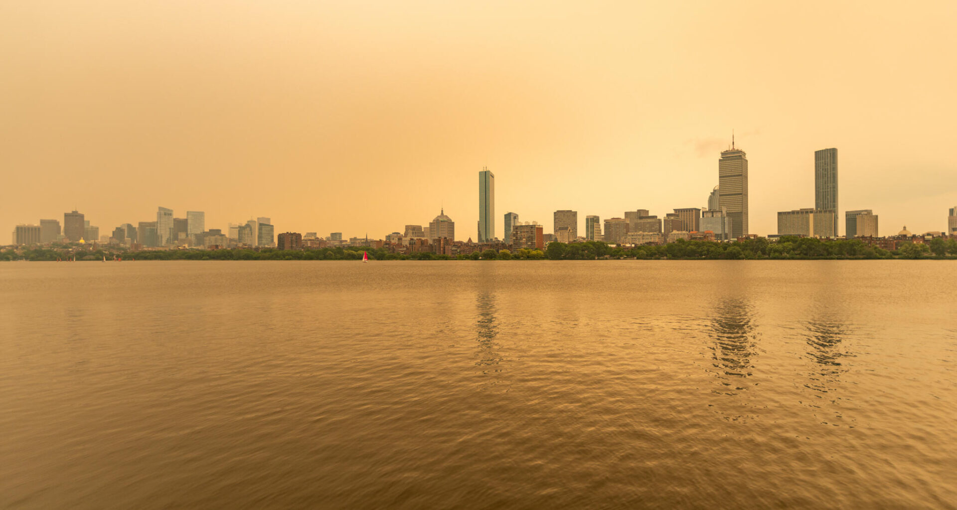 The Boston skyline along the Charles River as seen around noon on Wednesday as wildfire smoke from Canada creates a yellow haze. (Jesse Costa/WBUR)