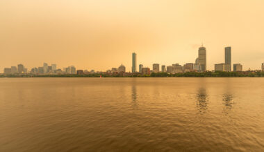 The Boston skyline along the Charles River as seen around noon on Wednesday as wildfire smoke from Canada creates a yellow haze. (Jesse Costa/WBUR)