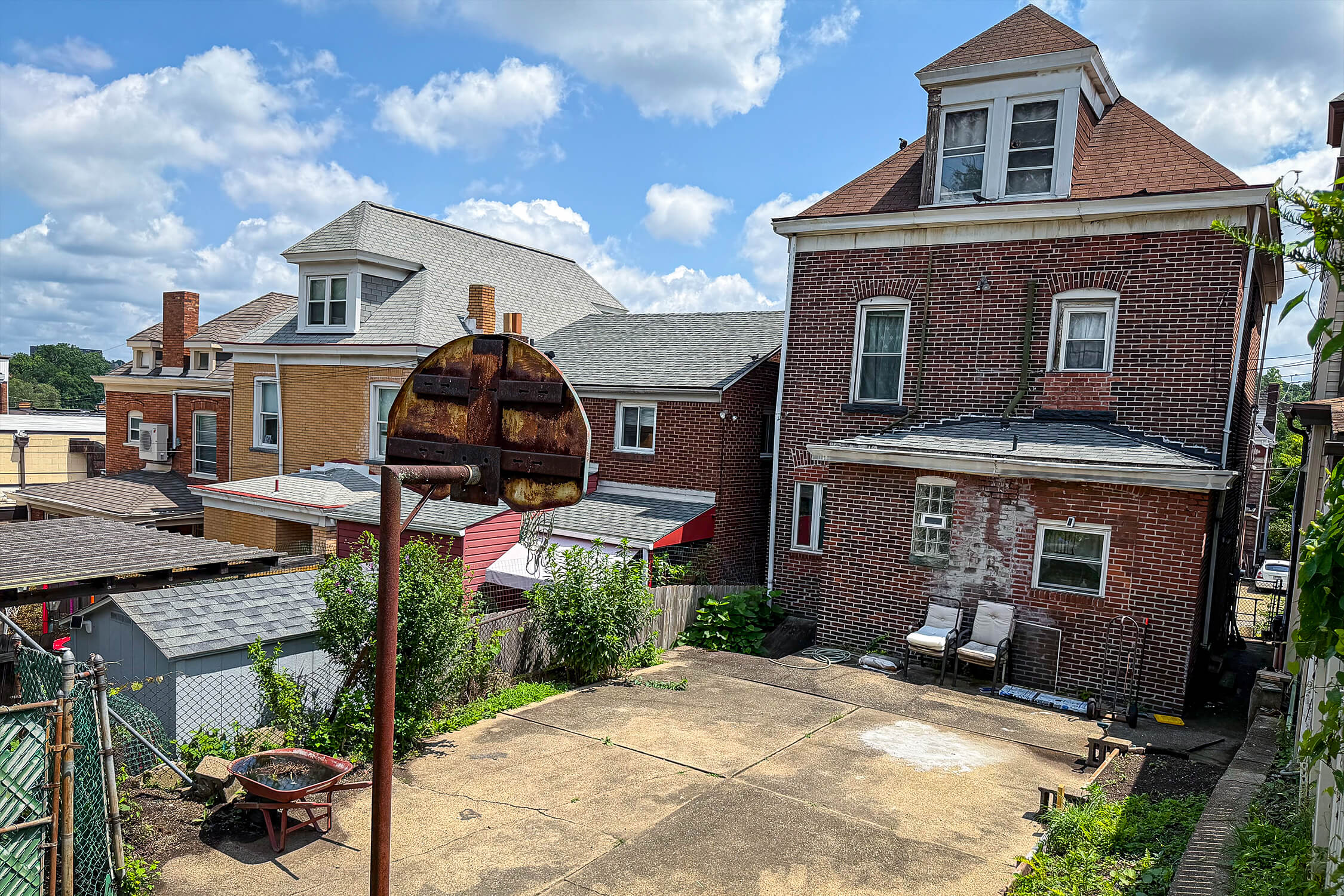 A high-angle photo of the backyard at Mike McCarthy's childhood home, including a basketball hoop held up by a rust-covered pole.