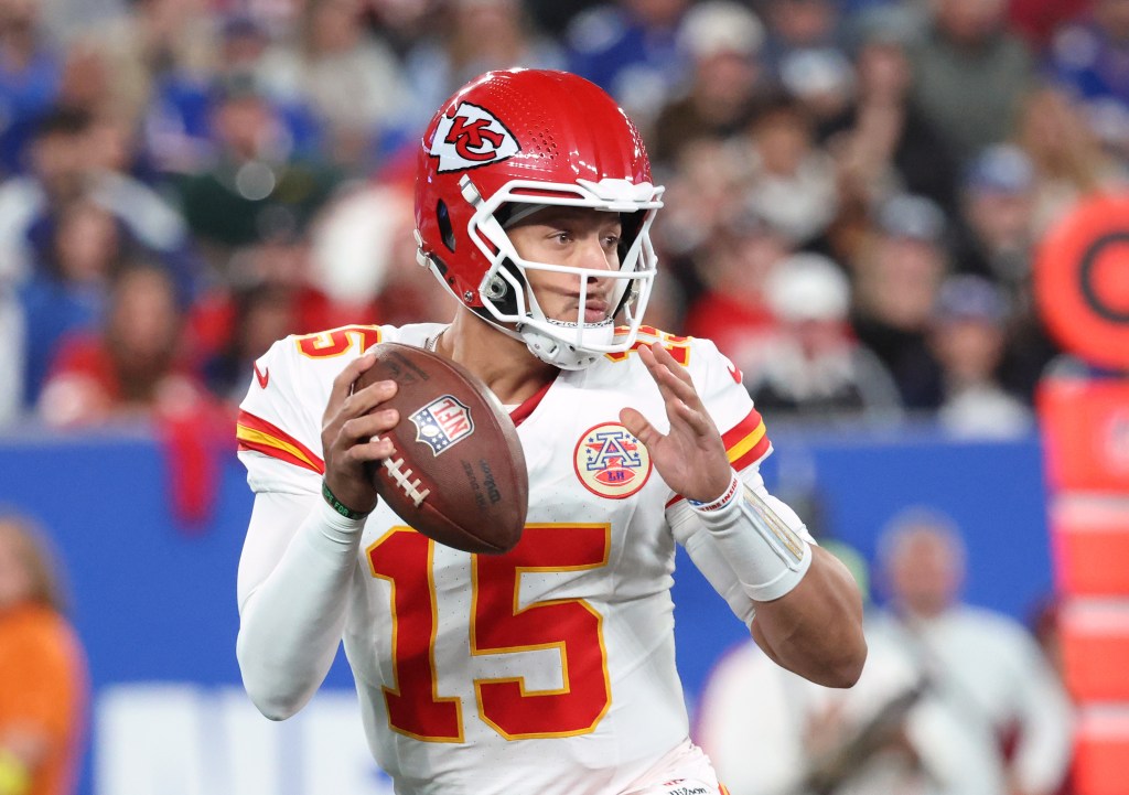 Patrick Mahomes #15 of the Kansas City Chiefs in a white jersey and red helmet with a football in hand.
