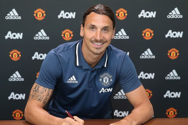 Zlatan Ibrahimovic smiling and signing his contract for Manchester United in 2016