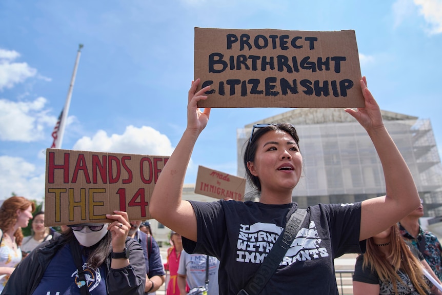 A woman holds a sign saying "protect birthright citizenship" in front of the US supreme court