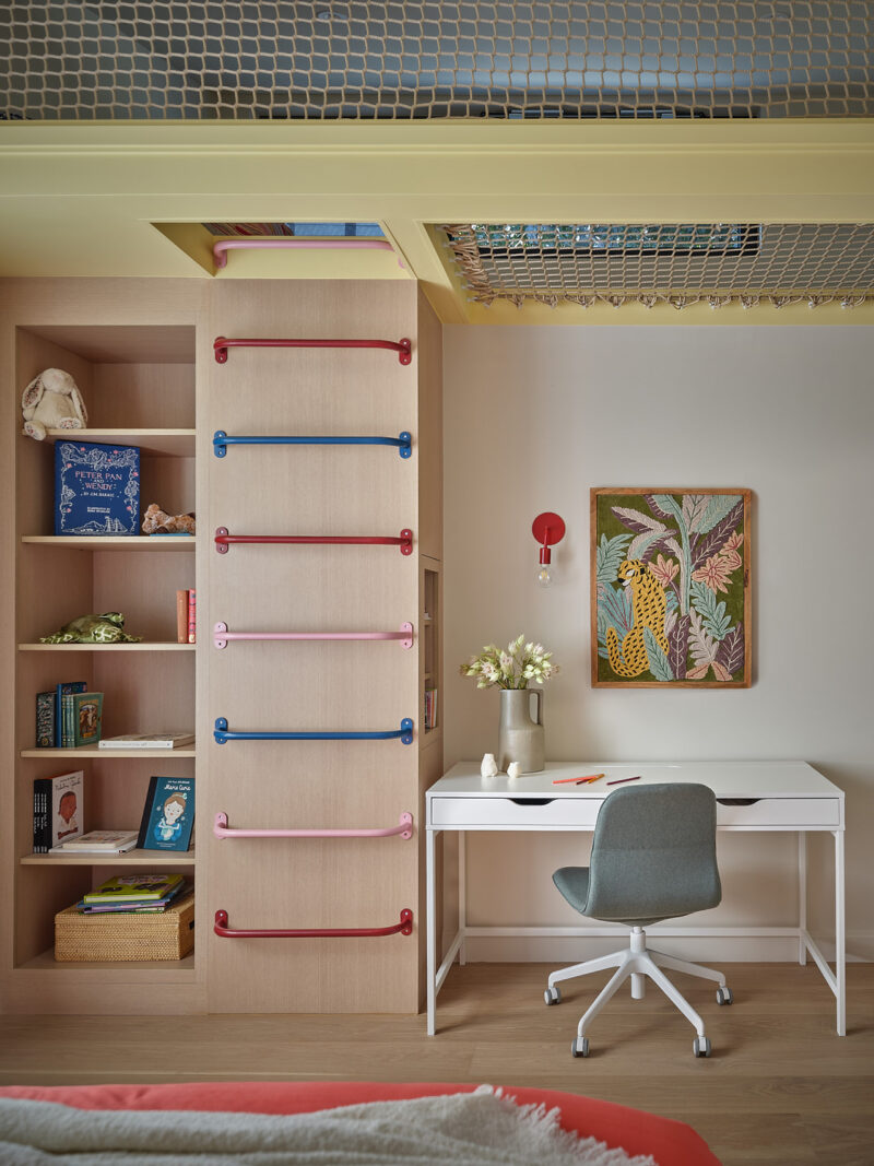Children’s bedroom in a Gillian Gillies Net Zero Ready Home, featuring a climbing ladder, built-in shelves with books and toys, a white desk with a chair, flowers, and a framed botanical artwork on the wall.