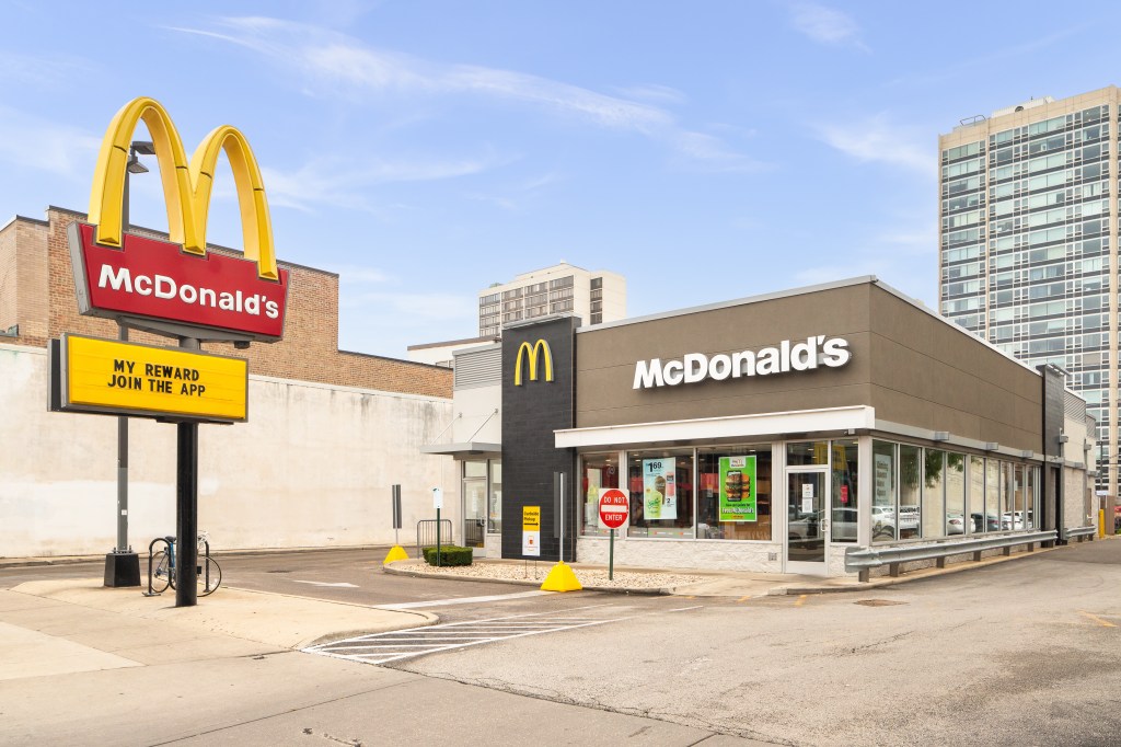 The storefront of a McDonald's restaurant in the city with a large Golden Arches sign and another sign advertising "My Reward Join the App."