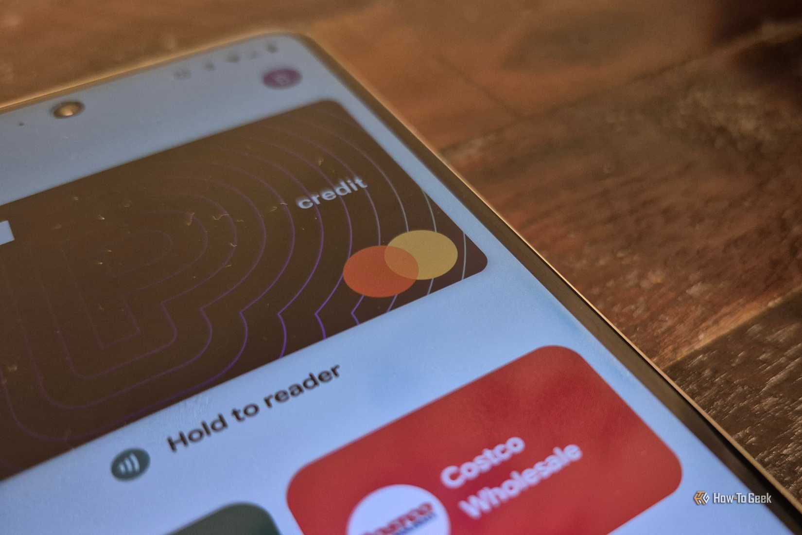 Cards open in the Google Wallet app on a phone resting on a wooden surface.