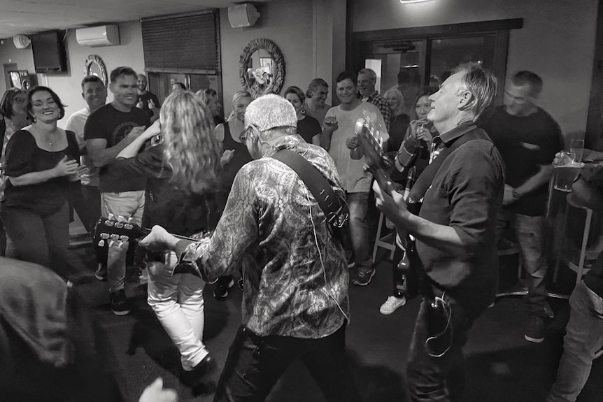 Two guitarists play as a crowd dances in front of them