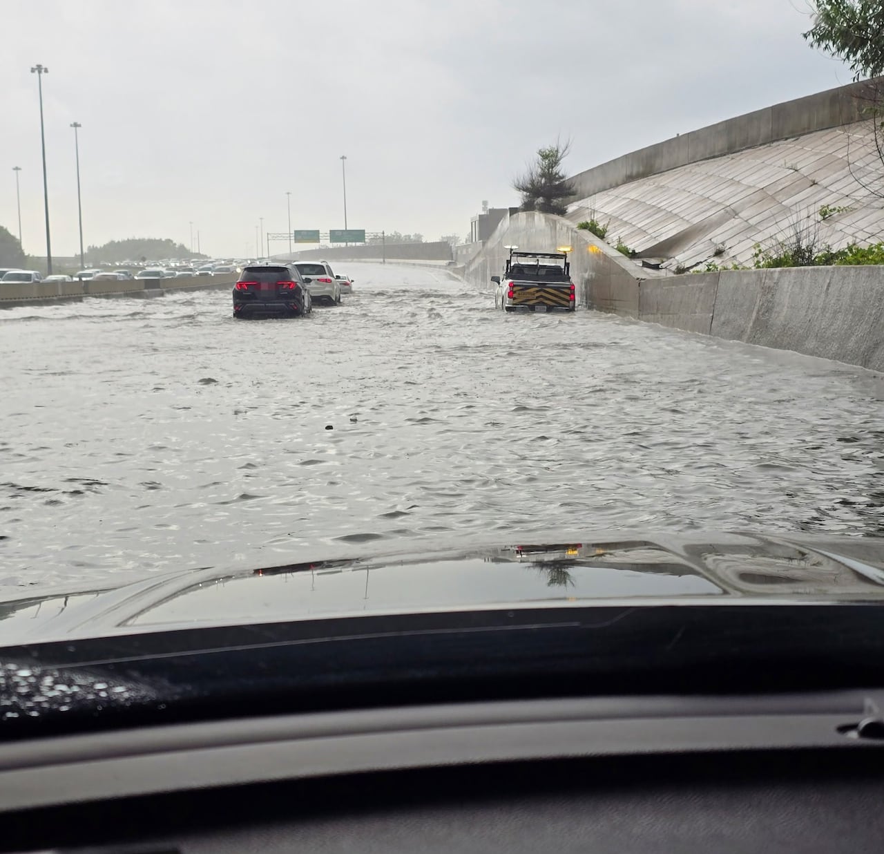 A picture out the front of a car of water on a highway.
