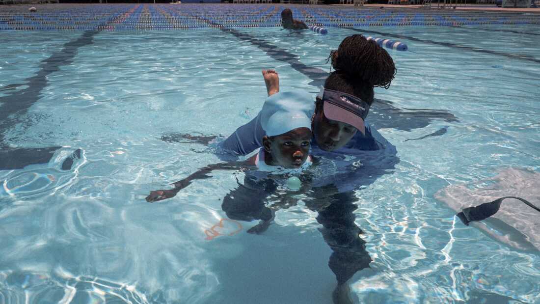 Garland Jones, recreational therapist and senior program director of the YMCA of South Florida’s special needs program, teaches Mackenzie Wesley, 5, to breathe safely in water by using a ping pong ball as a visual aid.