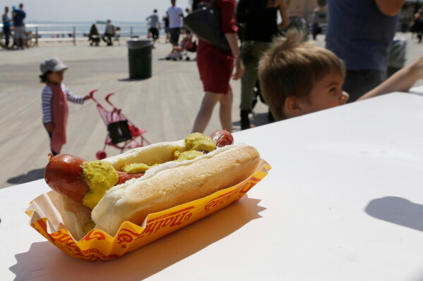 Pedestrians pass a Nathan's Famous hot dog on the Coney Island boardwalk, in the Brooklyn borough of New York on May 20, 2014. (AP Photo/Frank Franklin II, File)