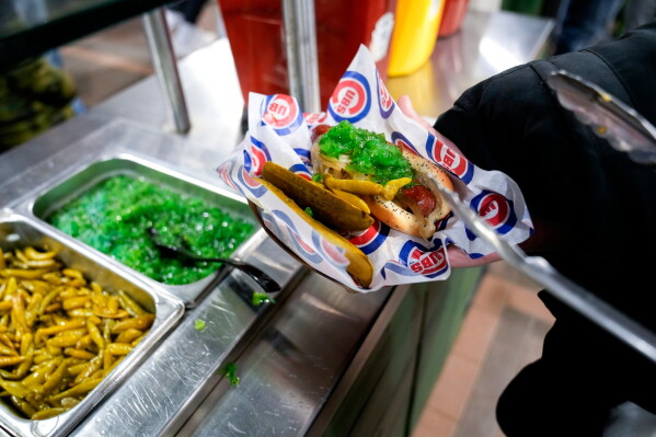 A fan puts sports peppers on a hot dog at Wrigley Field before the opening day baseball game between the Chicago Cubs and Milwaukee Brewers in Chicago on March 30, 2023. (AP Photo/Erin Hooley, File)