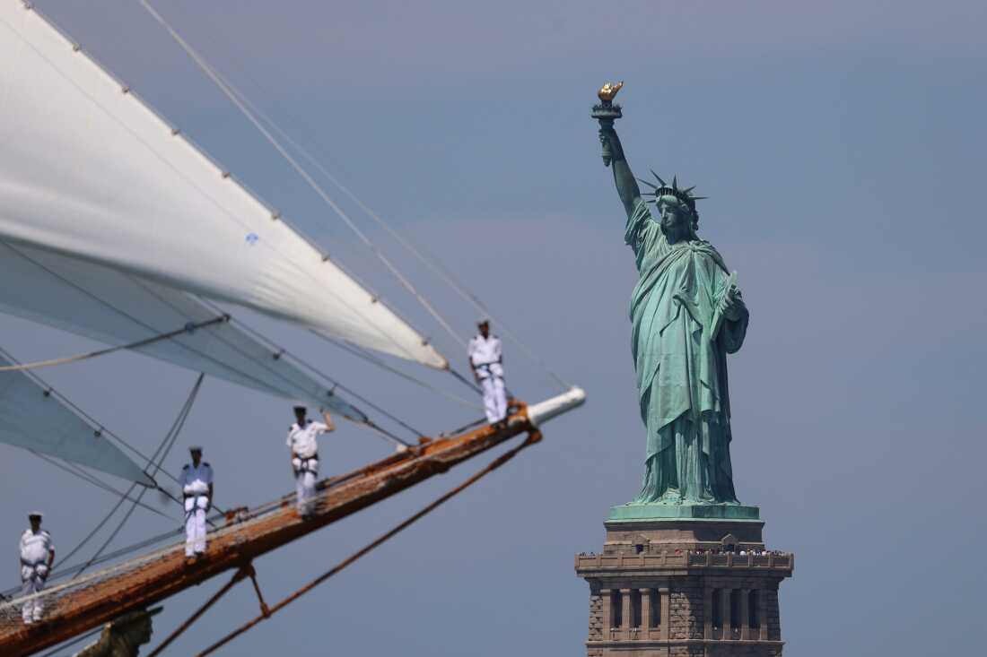 The Statue of Liberty is seen as sailors of a tall ship sail pass in the New York harbor during the International Parade of Sail, part of Sail250, a gathering of tall ships and military ships, Saturday, July 4, 2026, in New York.