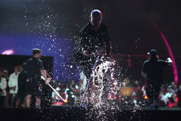 Workers clear water from the stage before President Donald Trump speaks at an Independence Day event honoring the nation's 250th anniversary, Saturday, July 4, 2026, on the National Mall in Washington. (AP Photo/Mark Schiefelbein)