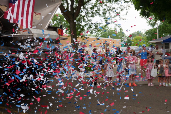 People watch as a truck blows red, white and blue confetti during an Independence Day parade, Saturday, July 4, 2026, in Deforest, Wis. (AP Photo/Jon Elswick)