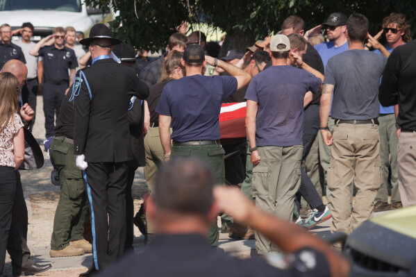 The body of a firefighter who died battling wildfires near the Colorado-Utah border is carried during a procession in Grand Junction, Colo., Monday, June 29, 2026. (AP Photo/Ty ONeil)