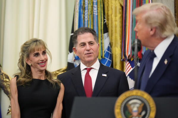President Donald Trump looks at Susan and Michael Dell after ringing the opening bell for the New York Stock Exchange and the Nasdaq in the Oval Office at the White House, Monday, July 6, 2026, in Washington. (AP Photo/Mark Schiefelbein)