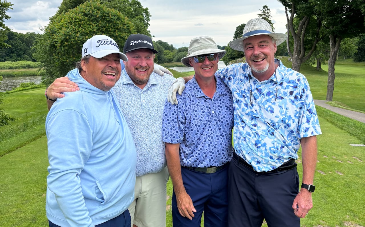 Four male golfers pose for a photo together