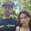 In this photo, Chloe Troub stands on the right side of the frame, and her boyfriend, Carson McDonald, is standing on the left side of the frame. Standing outdoors, they are photographed from about the shoulders up, and trees are in the background.