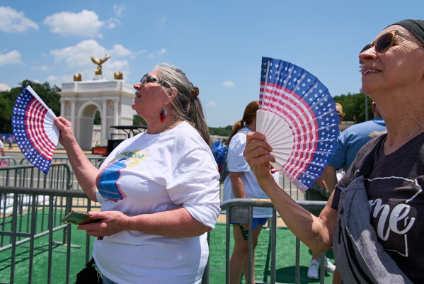 Mickelina Papotto, of Salem, Ore., left, and Lorie Odegaard, of Gaithersburg, Md., fan themselves while waiting in line for the ferris wheel at the Great American State Fair on the National Mall, July 1, 2026, in Washington. (AP Photo/Jacquelyn Martin)