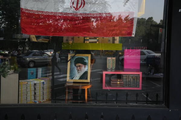 A portrait of the late Iranian Supreme Leader Ayatollah Ali Khamenei and an Iranian flag are displayed in the window of a bookstore ahead of Khamenei's funeral ceremonies, in Tehran, Iran, Thursday, July 2, 2026. (AP Photo/Vahid Salemi)