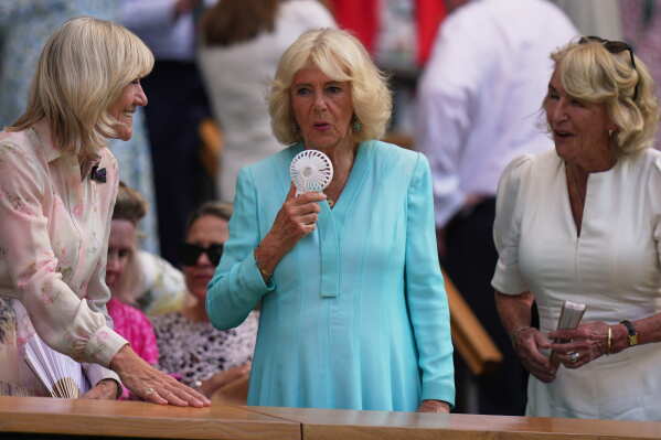 Britain's Queen Camilla uses a handheld fan to cool herself down as she sits in the royal box on day 10 of the Wimbledon Tennis Championships in London, Wednesday, July 8, 2026. (AP Photo/Brian Inganga)