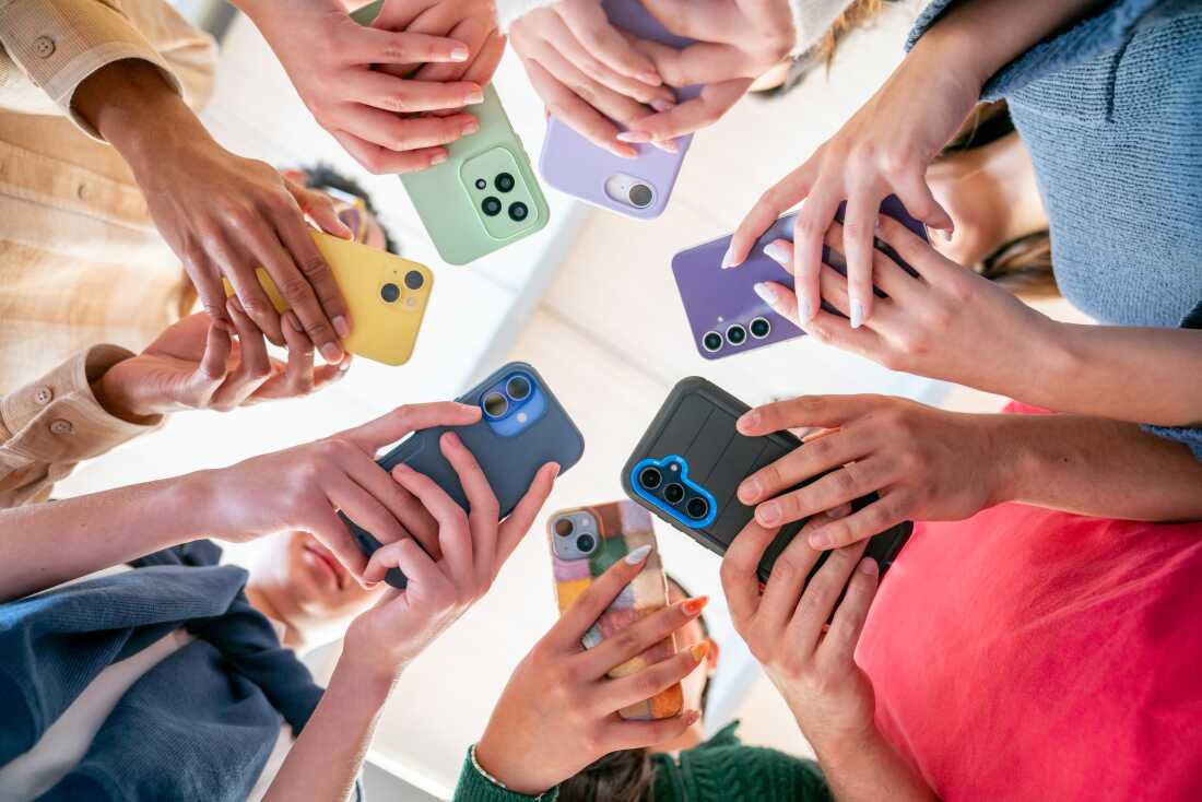 Group of Gen Z friends in a circle holding their phones.