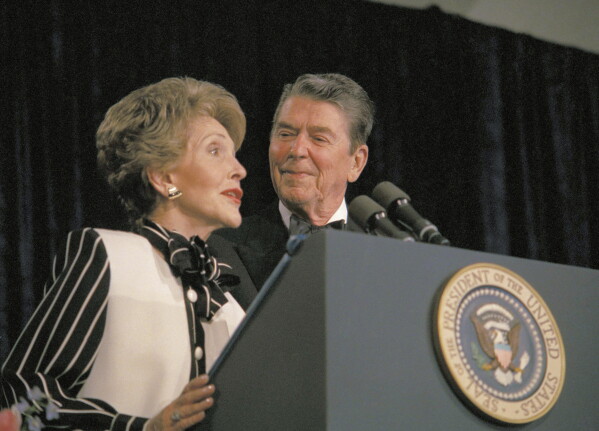 President Ronald Reagan watches as first lady Nancy Reagan comments from the podium during the White House Correspondents' Association annual dinner on April 23, 1987, in Washington. (AP Photo/Charles Tasnadi, File)
