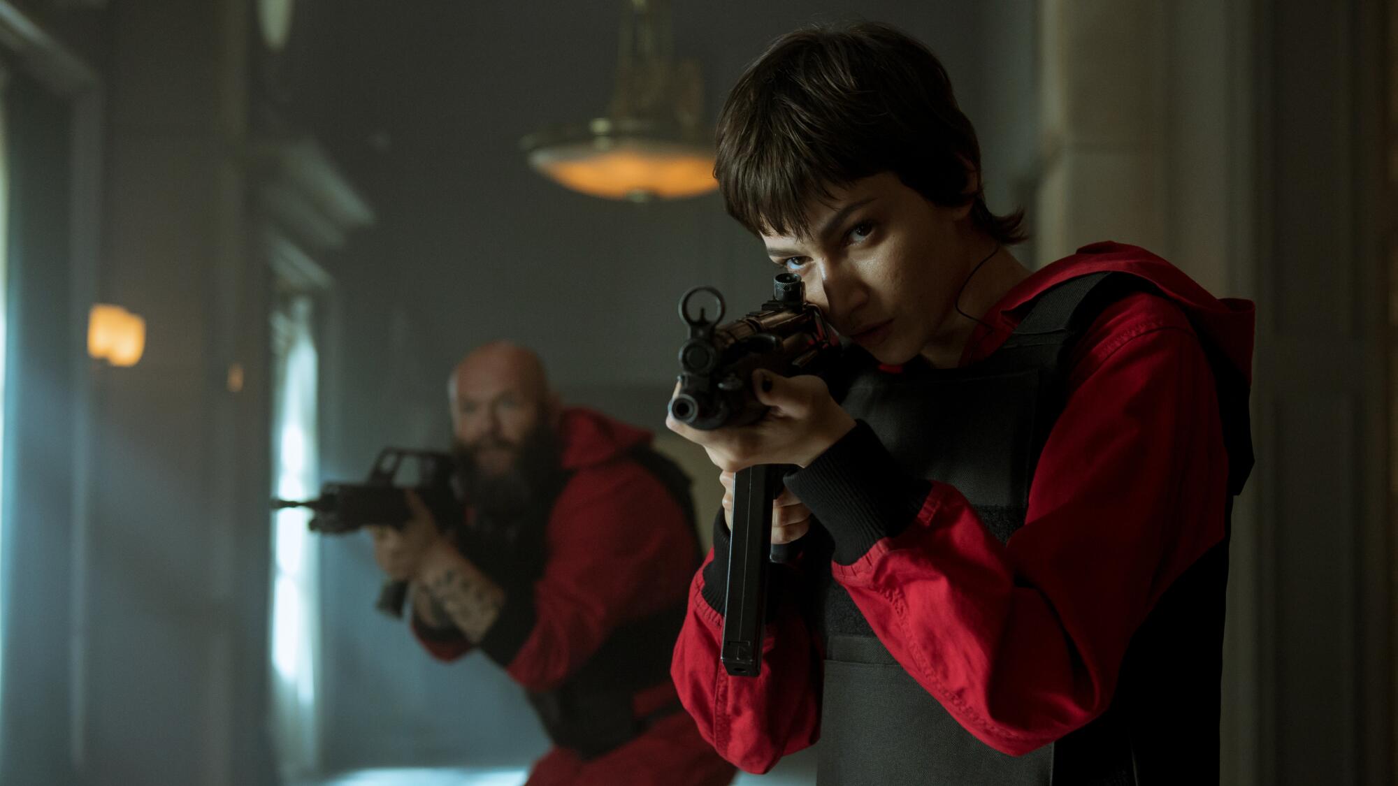 A man and a woman hold up guns in "Money Heist."