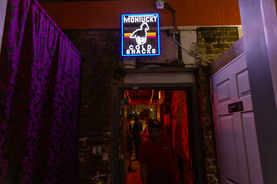 A patron enters the bar from the patio under the neon light decor at Nighthawk in Chicago on May 15.