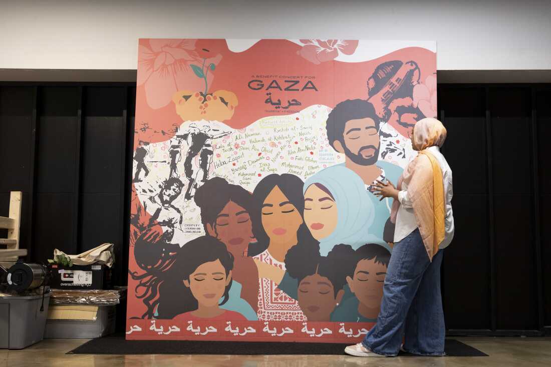 Jannah Sellars, the creative and cultural organizing manager at Inner-City Muslim Action Network (IMAN), shows a piece of art by Shrine Damra made for a Gaza benefit concert, that is now displayed in the Arts Lounge at IMAN headquarters in Chicago.