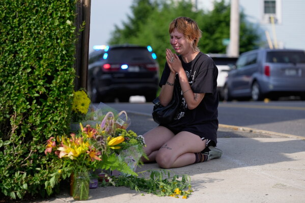 A woman prays after leaving flowers near the scene where a man was shot and killed by U.S. Immigration and Customs Enforcement on Monday, July 13, 2026, in Biddeford, Maine. (AP Photo/Robert F. Bukaty)