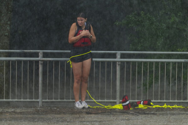 A woman stands on a sidewalk after being rescued from flood waters by members of the Boerne Fire Dept. on Wednesday, July 15, 2026, in Boerne, Texas. (AP Photo/Darren Abate)