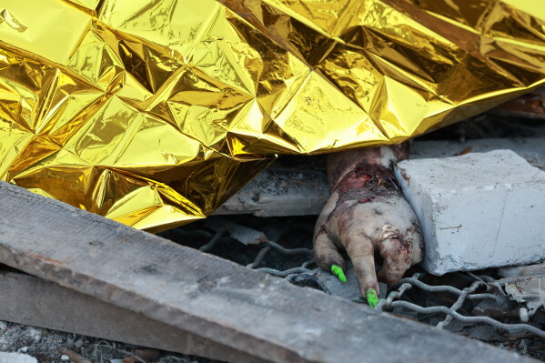 The body of a local resident is covered after a Russian air guided bomb hit private houses in Zaporizhzhia, Ukraine, Thursday, July 16, 2026. (AP Photo/Kateryna Klochko)