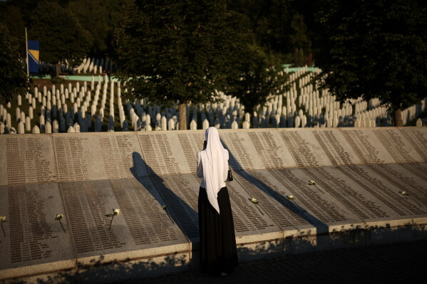 A woman stands next to the monument bearing the names of the victims of the Srebrenica genocide, at the Srebrenica Memorial Center in Potocari, Bosnia, Saturday, July 11, 2026. (AP Photo/Armin Durgut)