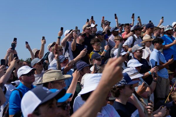 Spectators hold up their phones to capture Rory McIlroy of Northern Ireland and Shane Lowry of Ireland during their practice round for the British Open Golf championships at Royal Birkdale golf club, in Southport, England, Wednesday, July 15, 2026. (AP Photo/David Goldman)