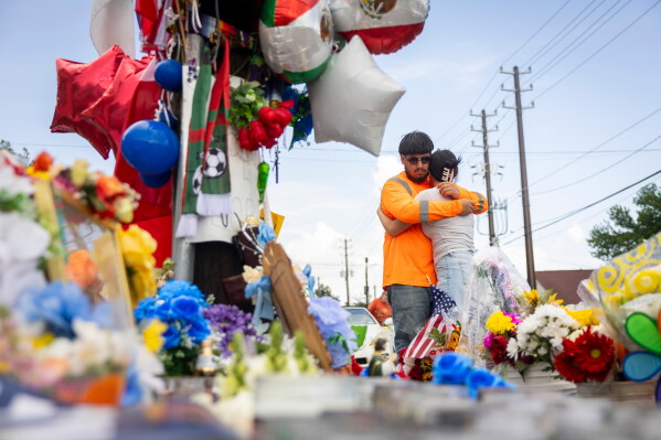 Albert Salgado is comforted by his girlfriend at the site where his uncle Lorenzo Salgado Araujo was shot by an ICE officer in Houston on Friday, July 10, 2026. (AP Photo/Annie Mulligan)