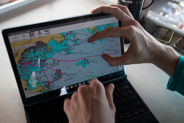 A researcher displays a tablet with a mapping system used to identify research sites for a shark project in Ilha Grande Bay, Angra dos Reis, Rio de Janeiro state, Brazil, July 14, 2026. (AP Photo/Bruna Prado)