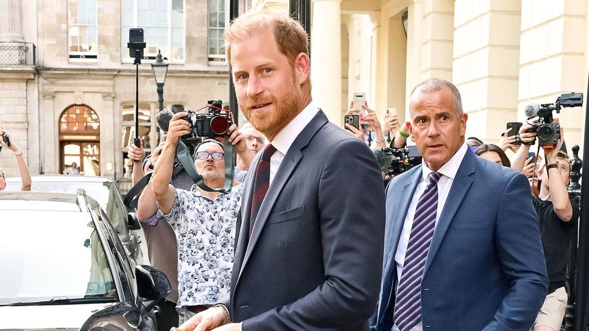Prince Harry leaving Chatham House in London with security behind him.