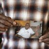 A close-up photo shows Leslie Adams' hands holding a snapshot of his mother. She is smiling broadly.