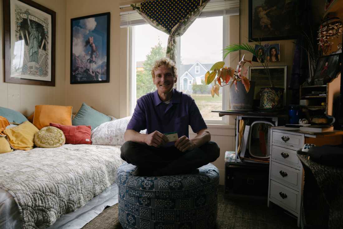 Cody Coughenhour, at home in his bedroom, holds his health insurance card.