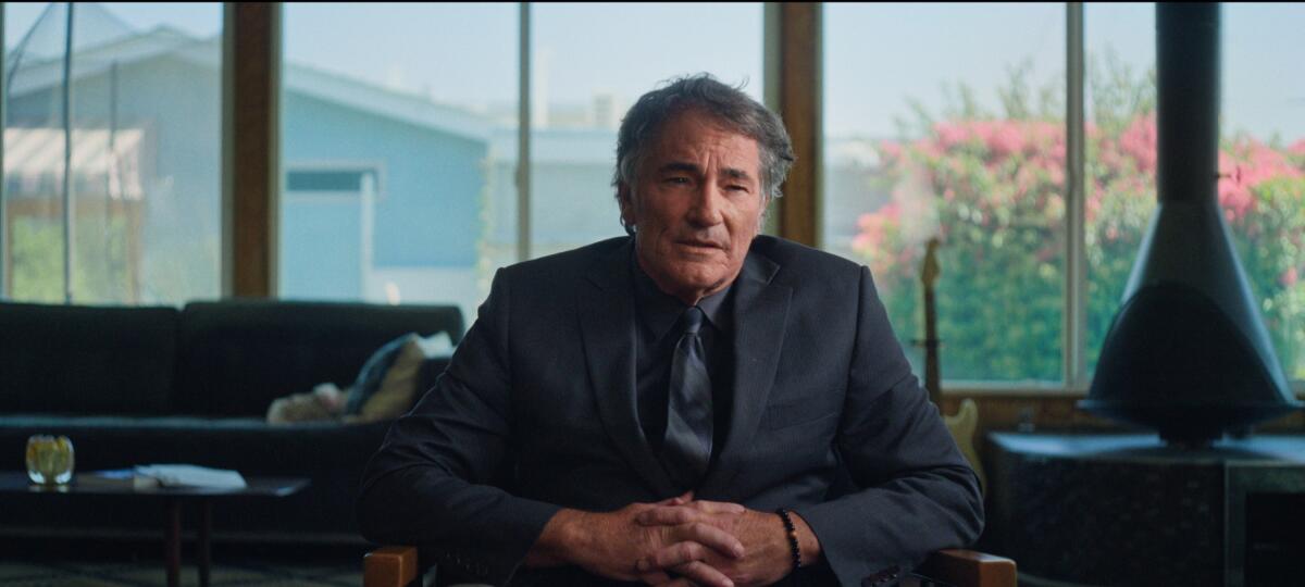 A man in a dark suit and tie sitting in a living room.
