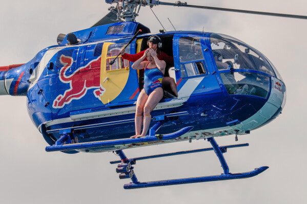 This image released by Discovery Channel shows high diver Molly Carlson preparing to leap 50 feet from a helicopter into a cage surrounded by reef sharks in an episode for Discovery's annual "Shark Week." (Tito Herrera/Discovery Channel via AP)
