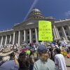 Protesters hold signs in front the of the Utah State Capitol building to oppose the construction of the Stratos data center on May 23, 2026 in Salt Lake City, Utah. The most prominent sign in the photo reads: "DON'T LET BILLIONAIRES DESTROY OUR HOME!"