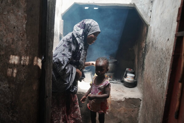 Maryam Aminu stands next to her daughter Farisa, who has relapsed into malnutrition, in front of their kitchen in Kware Sokoto, northwestern Nigeria, Wednesday, July 15, 2026. (AP Photo/Sunday Alamba)