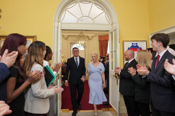 Staff clap as new Prime Minister Andy Burnham and wife Marie-France van Heel walk into 10 Downing Street in London, Monday, July 20, 2026. (AP Photo/Kin Cheung, Pool)