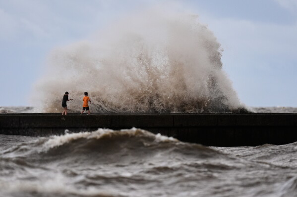 Children play near breaking waves on West End Pier on Lake Pontchartrain as Tropical Storm Bertha approaches the Louisiana Coast Wednesday, July 22, 2026, in New Orleans. (AP Photo/Gerald Herbert)